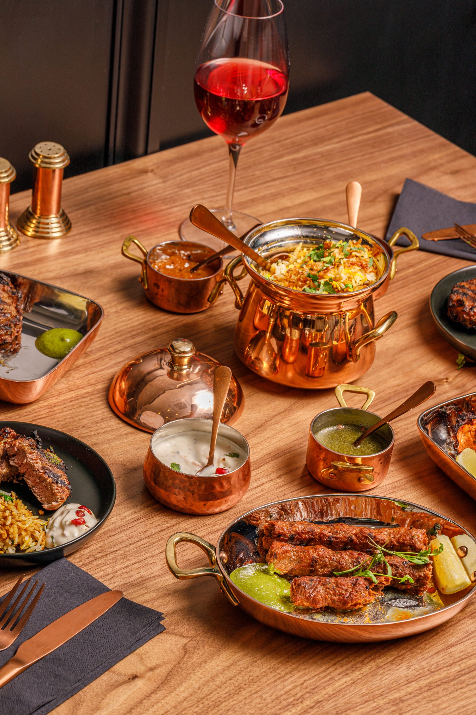 A table of biryani, seekh kebabs and sides served in copper at Madhu’s Brasserie Richmond