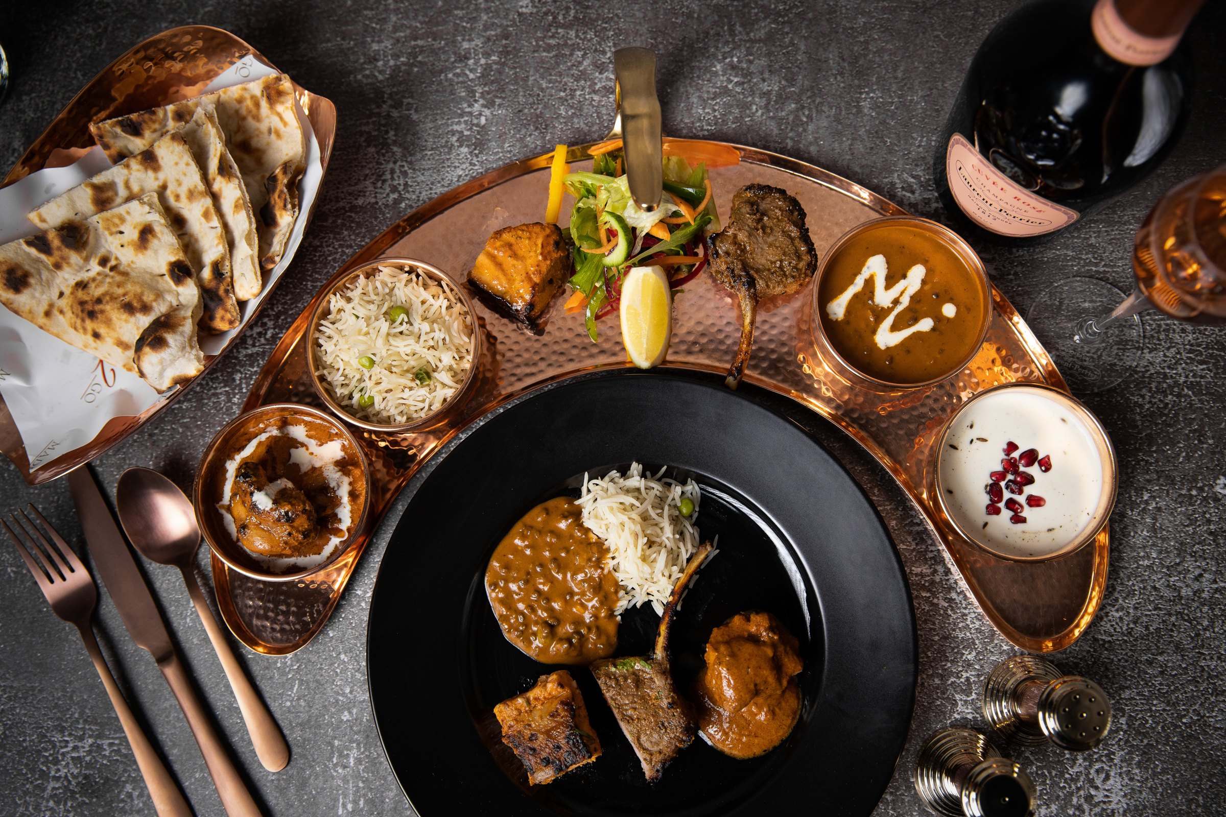 Signature platter of curries, lamb chops, rice and naan in hammered copper
