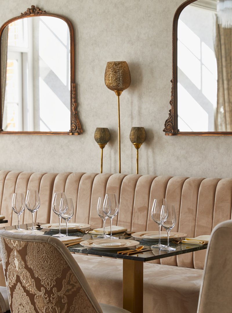 Dining room at Madhu's at The Grove with velvet banquette and gilded mirrors