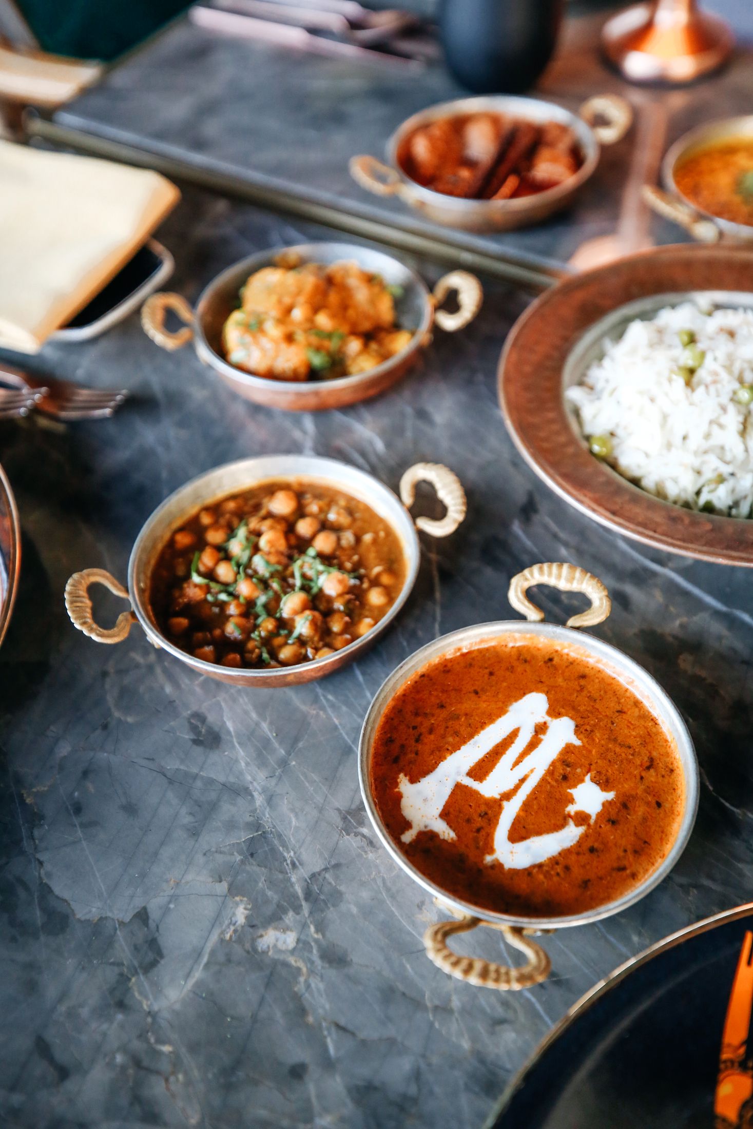 Curries in hammered copper, one finished with the Madhu's M