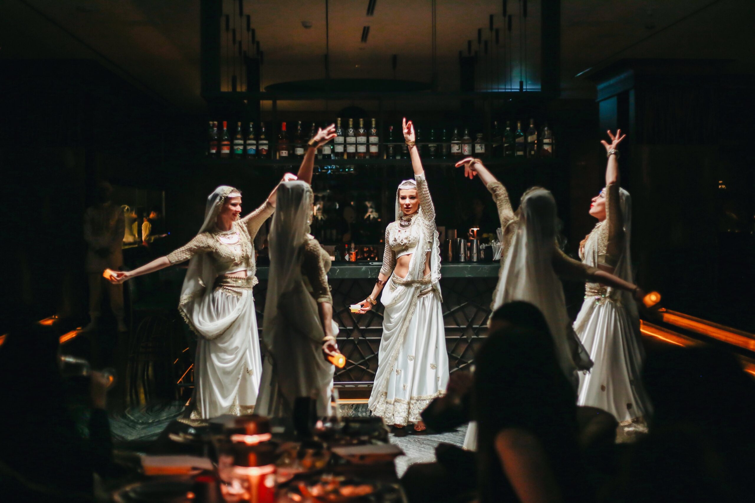 Dancers in white and gold performing by the bar