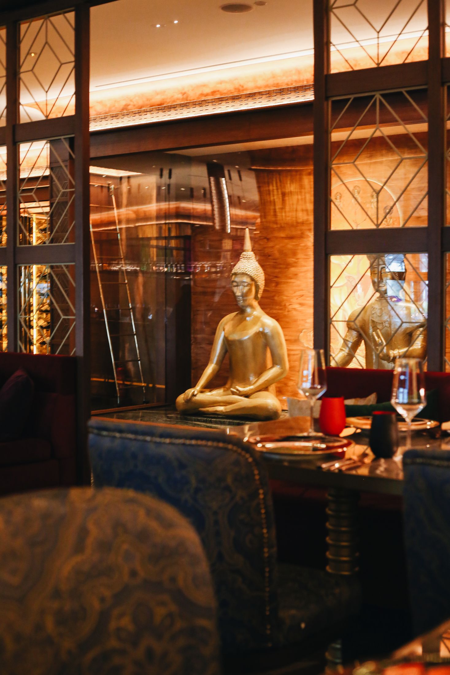 A golden seated Buddha behind lattice glass